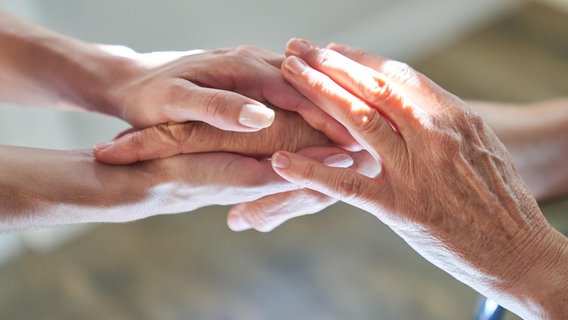 Junge Frauenhände umfassen die Hände einer Seniorin. © picture alliance / Zoonar | Robert Kneschke Foto: picture alliance
