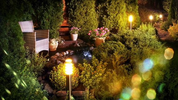 Kleine Lampen beleuchten einen kleinen Pfad in einen Garten. © Colourbox 