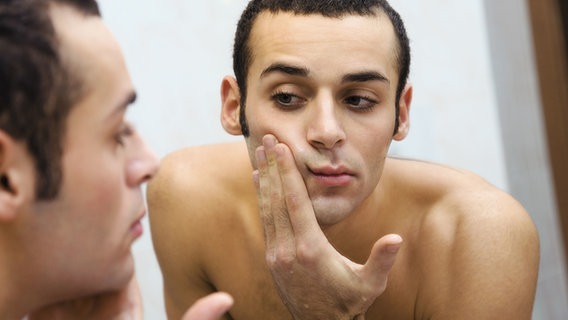 Ein Mann schmiert sein Gesicht mit Aftershave ein. © Picture-Alliance / Bildagentur-online 