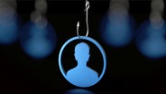Symbolbild zum Thema Online-Betrug: Eine aus Holz geschnitze Figur hängt an einem Angelhaken. © picture alliance / Zoonar | DesignIt 