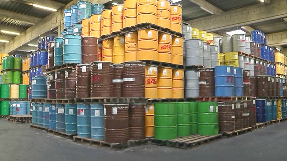 Halle mit riesigen Stapeln von Metallfässern, in denen Honig gelagert wird. © NDR TOB Film 
