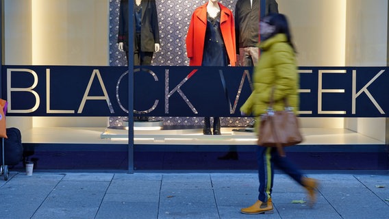 Eine Passantin vor einem Schaufenster, in dem ein Plakat mit der Aufschrift "Black Week" hängt © Marcus Brandt/dpa Foto: Marcus Brandt