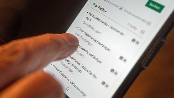 Ein Zeigefinger tippt auf einem Smartphone auf eine Schaltfläche zum digitalen Beantragen eines Personalausweises. © dpa Foto: Frank Rumpenhorst