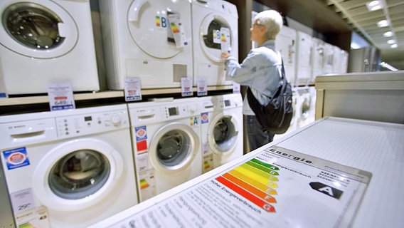 Eine Frau schaut sich in einem Geschäft die Energielabel auf Waschmaschinen an. © imago Foto: Bernhard Classen