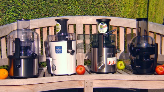 Vier Entsafter unterschiedlicher Hersteller stehen auf einer Gartenbank aus Holz. © WDR / NDR Fernsehen 