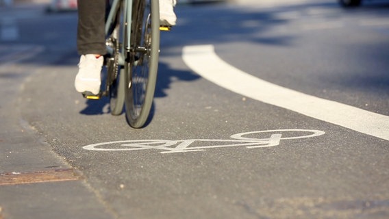 Radfahrstreifen mit einem Radfahrer. Aufgenommen aus der Froschperspektive. Vom Radfahrer sind nur die Füße zu sehen. © NDR 