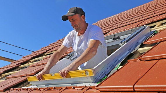 Ein Handwerker baut ein neues Dachfenster ein. © picture alliance / CHROMORANGE Foto: Udo Herrmann