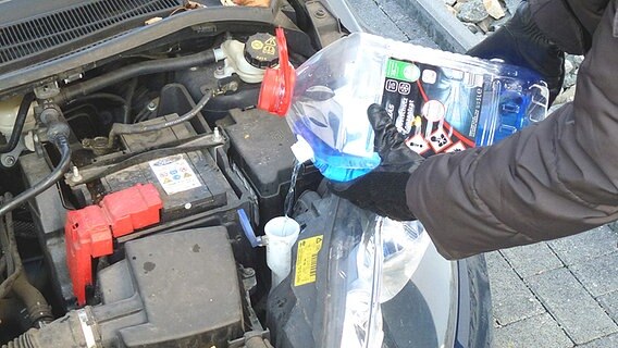 Blauer Frostschutz wird in den Behälter einer Scheibenwaschanlage eines Autos gefüllt. © Axel Franz Foto: Axel Franz