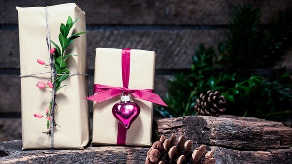 Zwei Geschenke, in Packpapier verpackt, dekoriert mit Zweigen und Beeren. © NDR Foto: Anja Deuble