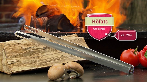 Eine Grillzange der Firma Höfats liegt auf einem Tisch vor einem Grill. © WDR 