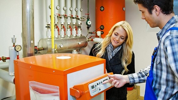 A man and a woman are standing at a boiler in a boiler room.  © imago images / perspective 