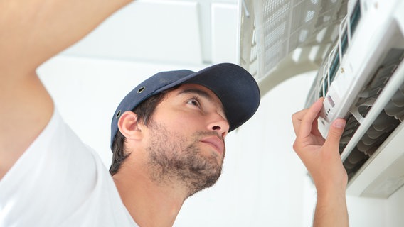 Ein Mann installiert ein Klimagerät © Colourbox Foto: Phovoir