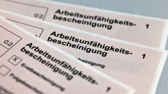 Drei Arbeitsunfähigkeitsbescheinigungen aus Papier liegen auf einem Tisch © Jens Büttner/dpa-Zentralbild/dpa Foto: Jens Büttner