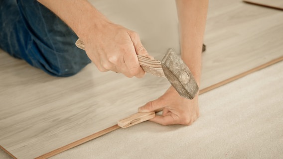 Ein Mann verlegt einen Laminatboden. © Colourbox Foto: -