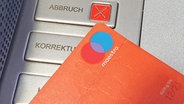 Eine Girocard mit Maestro-Funktion in Nahaufnahme vor einem Geldautomaten. © picture alliance Foto: Eibner-Pressefoto
