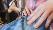 Es wird an einer Jeans mit der Nähmaschine genäht. © panthemedia Foto: mitarart