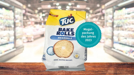 Eine Packung Brotchips "Tuc Bake Rolls" vor Supermarkt-Regalen, "Mogelpackung des Jahres" 2023 © Verbraucherzentrale Hamburg, Canva.com 