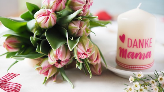 Tulpen liegen auf einem Tisch, eine  Kerze mit "Danke, Mama"  steht daneben. © NDR Foto: Anja Deuble