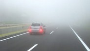 Ein Auto fährt bei Nebel mit eingeschalteter Nebelschlussleuchte. © imago/McPhoto 