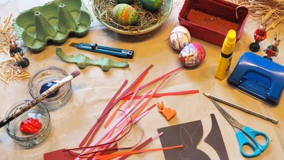 Material für das Osterbasteln liegt auf dem Tisch: Papier, Farben, Pinsel, Kleber, Eier, Heu und Stroh. © NDR Foto: Anja Deuble