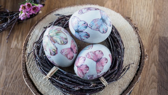 Mit Schmetterlingen gestaltete Eier liegt in einem Nest aus Birkenreisig. © NDR Foto: Anja Deuble