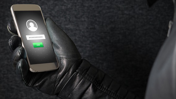 Mann mit Lederhandschuh schaut auf ein Smartphone Display. © fotolia Foto: terovesalainen