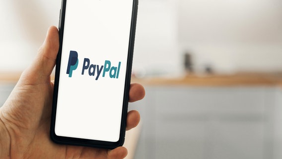 Eine Hand hält ein Smartphone, auf dem das Logo des Zahlungssystems Paypal zu sehen ist. © picture alliance, Michael Bihlmayer Foto: Michael Bihlmayer