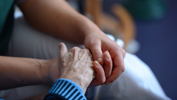 Ein Angehöriger hält die Hand seiner Großmutter ©  Jens Kalaene 