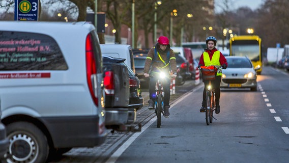 Zwei Radfahrer mit Leuchtwesten und-streifen im Straßenverkehr. © imago Foto: Jochen Tack