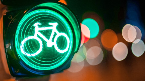 Großaufnahme des grünen Lichts an einer Radfahrer-Ampel. Verschwommene Lichter im nächtlichen Hintergrund. ©  picture alliance / dpa Foto: Hauke-Christian Dittrich