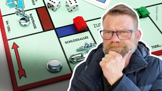 Im Hintergrund ist ein Ausschnitt eines Monopoly Spielbretts zu sehen. Rechts im Vordergrund sieht man den Reporter. © Imago Foto: HR Schulz