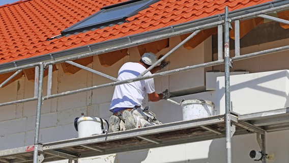 Ein Handwerker bringt eine Isolierung an einer Hausfassade an. © picture alliance / CHROMORANGE Foto: Udo Herrmann