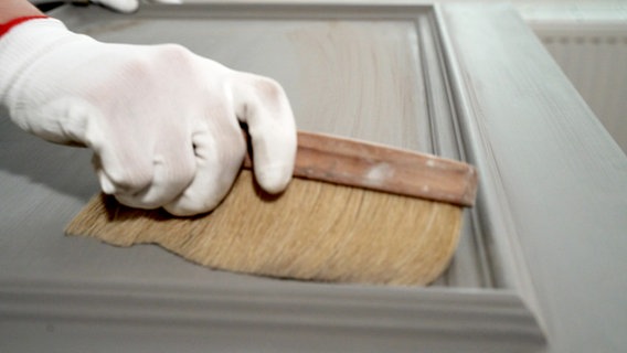 Mit einem Besen wird eine angeschliffene Holztür gereinigt. © NDR/nonfictionplanet 