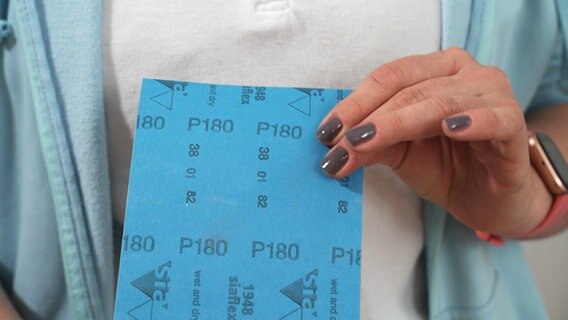 Auf der Rückseite eines Schleifpapiers steht eine Nummer. © NDR/nonfictionplanet 