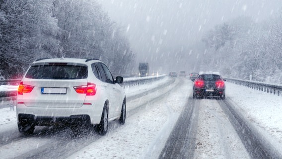 Autos fahren bei Schneetreiben auf einer verschneiten Straße.  © fotolia Foto: petair