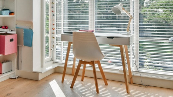 Ein kleiner weißer Schreibtisch mit Arbeitslampe und ein ein Stuhl vor einem Fenster © CasaMedia Charlotte Van Montpensierlaan Foto: CasaMedia Charlotte Van Montpensierlaan