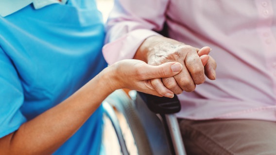 Zu sehen ist die Hand einer Pflegenden, welche die Hand einer pflegebedürftigen Person hält © colourbox.de /Kzenon Foto: Kzenon