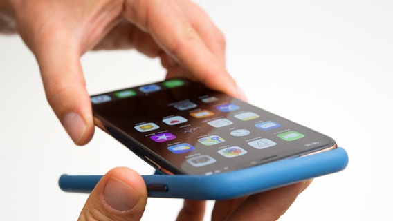 Ein Smartphone wird in eine Silikon-Hülle gesteckt. © Picture-Alliance / dpa Themendienst Foto: Andrea Warnecke