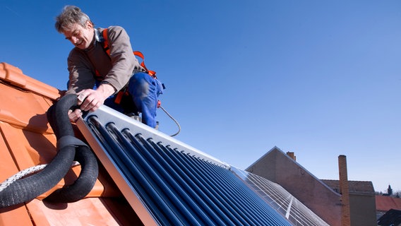 Ein Fachmann bringt eine solarthermische Anlage auf einem Dach an. © Bundesverband der deutschen Heizungsindustrie 