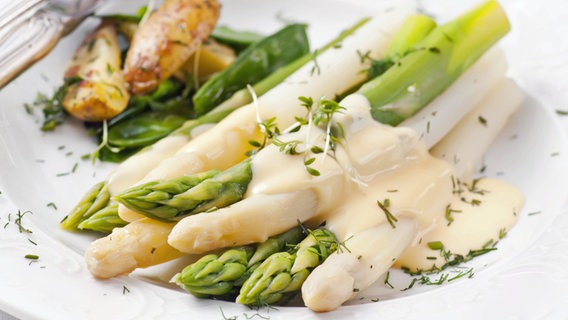 Grüner und weißer Spargel mit Sauce Hollandaise und Kartoffeln auf einem Teller serviert. © Fotolia.com Foto: HLPhoto