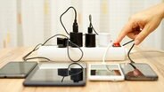 Eine Mehrfachsteckdose mit Schalter, an der verschiedene mobile Geräte hängen. © fotolia.com Foto: Bacho Foto