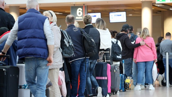 Des voyageurs font la queue à un comptoir d'enregistrement à l'aéroport de Hambourg © dpa-Bildfunk Photo : Bodo Marks
