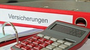 Symbolbild: Ordner mit Versicherungen und Taschenrechner auf einem Schreibtisch © picture alliance / CHROMORANGE Foto: Udo Herrmann