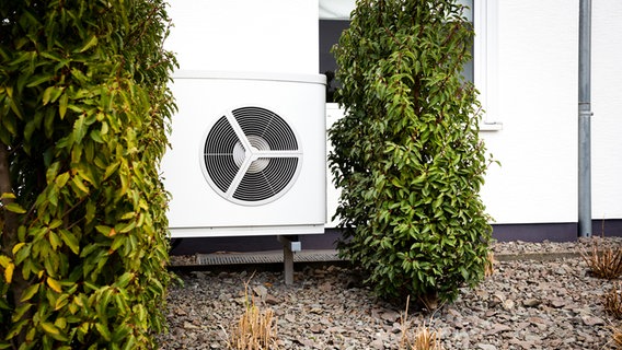 A heat pump is in the front yard of a house.  © Photocase photo: birdys