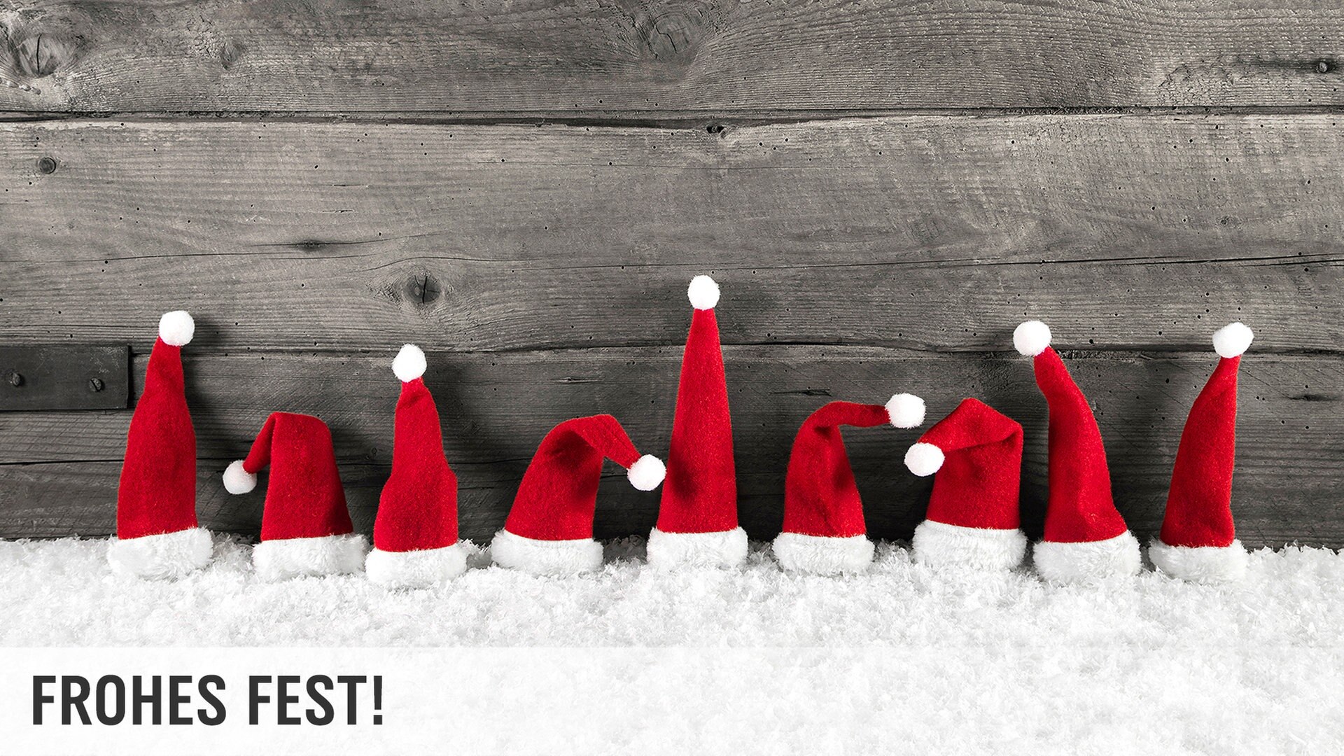 Kleine Weihnachtsmützen in einer Reihe vor Holzhintergrund © fotolia Foto: Jeanette
