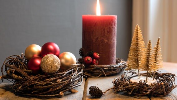 Drei selbst gebundene kleine Kränze sind mit Weihnachtskugeln und goldenen Tannenbäumchen dekoriert. © NDR Foto: Anja Deuble
