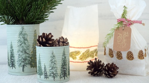 Konserverndosen und Butterbrottüten mit weihnachtlichen Motiven stehen auf einem Tisch. © NDR Foto: Anja Deuble