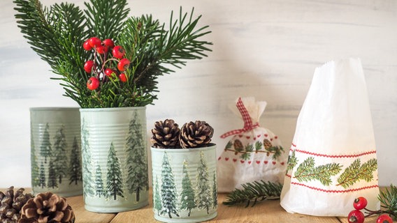 Konserverndosen und Butterbrottüten mit weihnachtlichen Motiven stehen auf einem Tisch. © NDR Foto: Anja Deuble