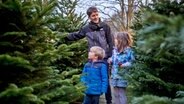 Ein Vater mit zwei Kindern beim Kauf eines Weihnachtsbaums. © picture alliance / dpa Themendienst Foto: Christin Klose