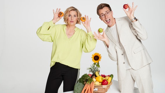 Die Moderatoren Dr. Johannes Wimmer und Elena Uhlig halten Obst und Gemüse in den Händen. © ARD 